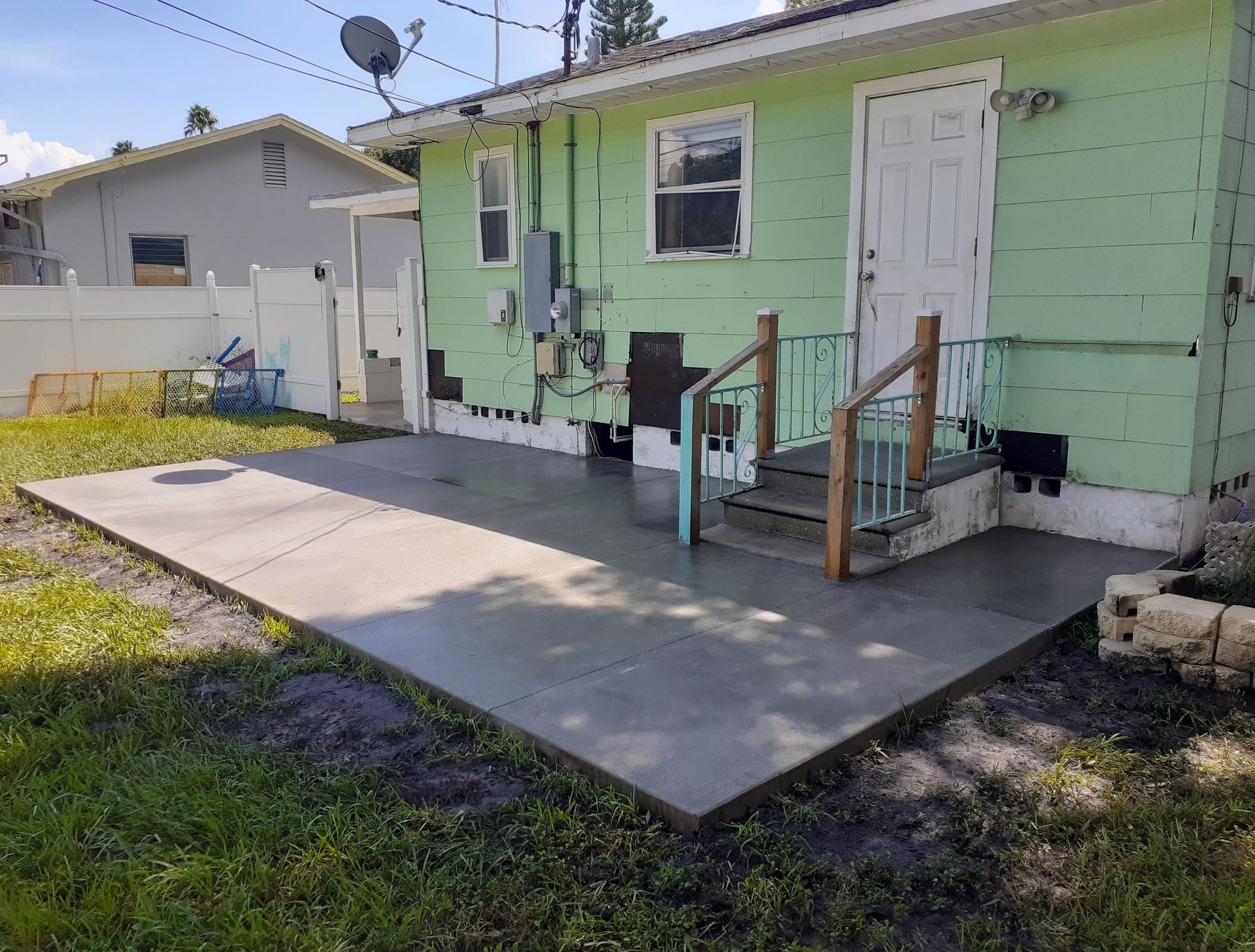 A green house with a concrete patio in front of it.