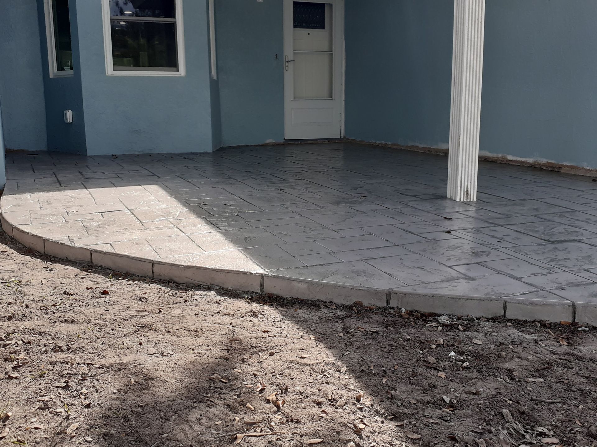 A blue house with a concrete patio in front of it