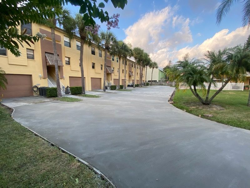 A concrete driveway leading to a row of apartment buildings