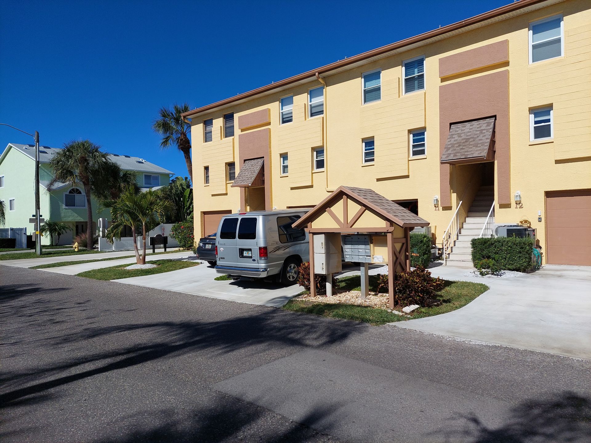 A white van is parked in front of a yellow building