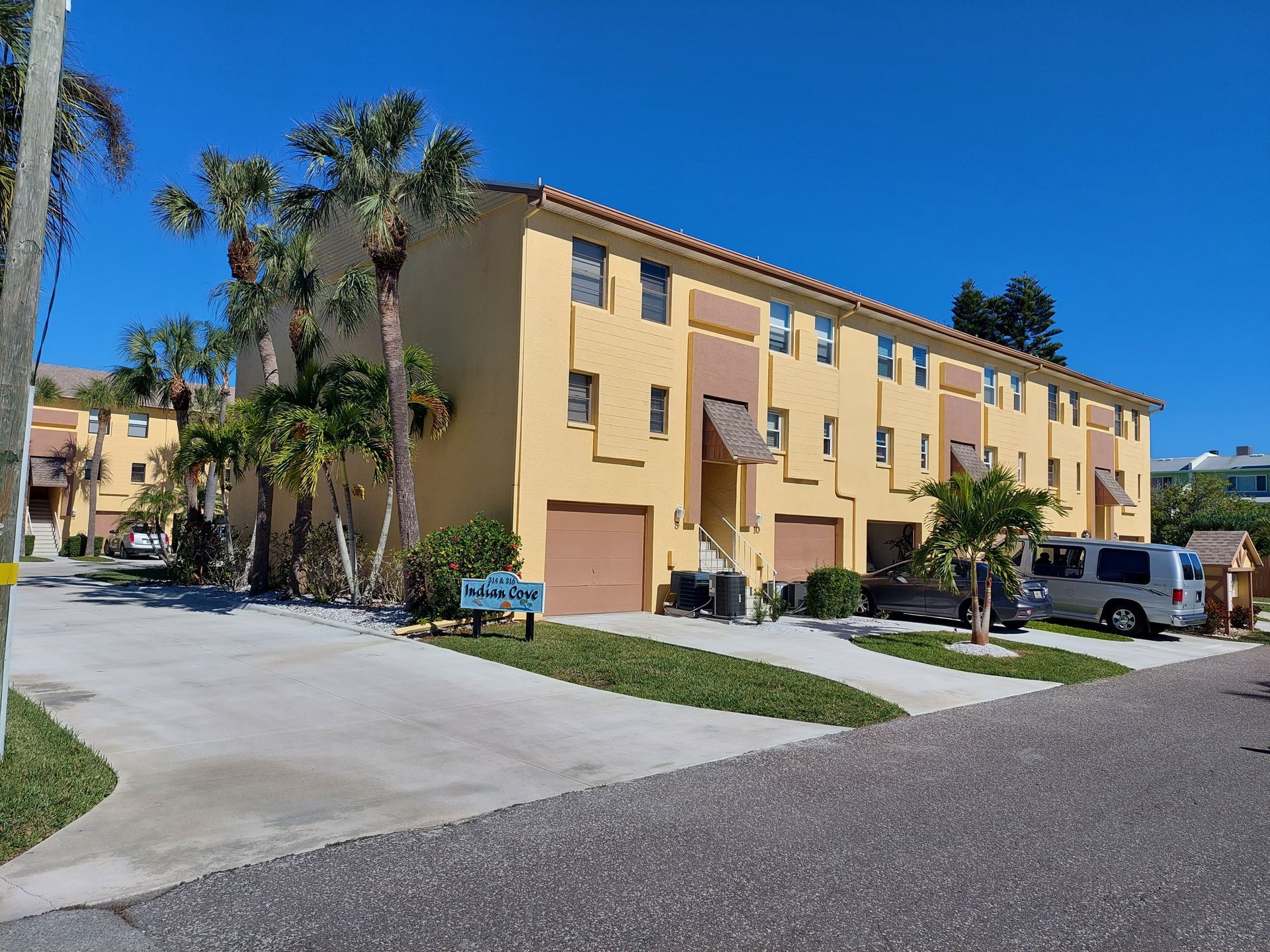 A row of apartment buildings with cars parked in front of them
