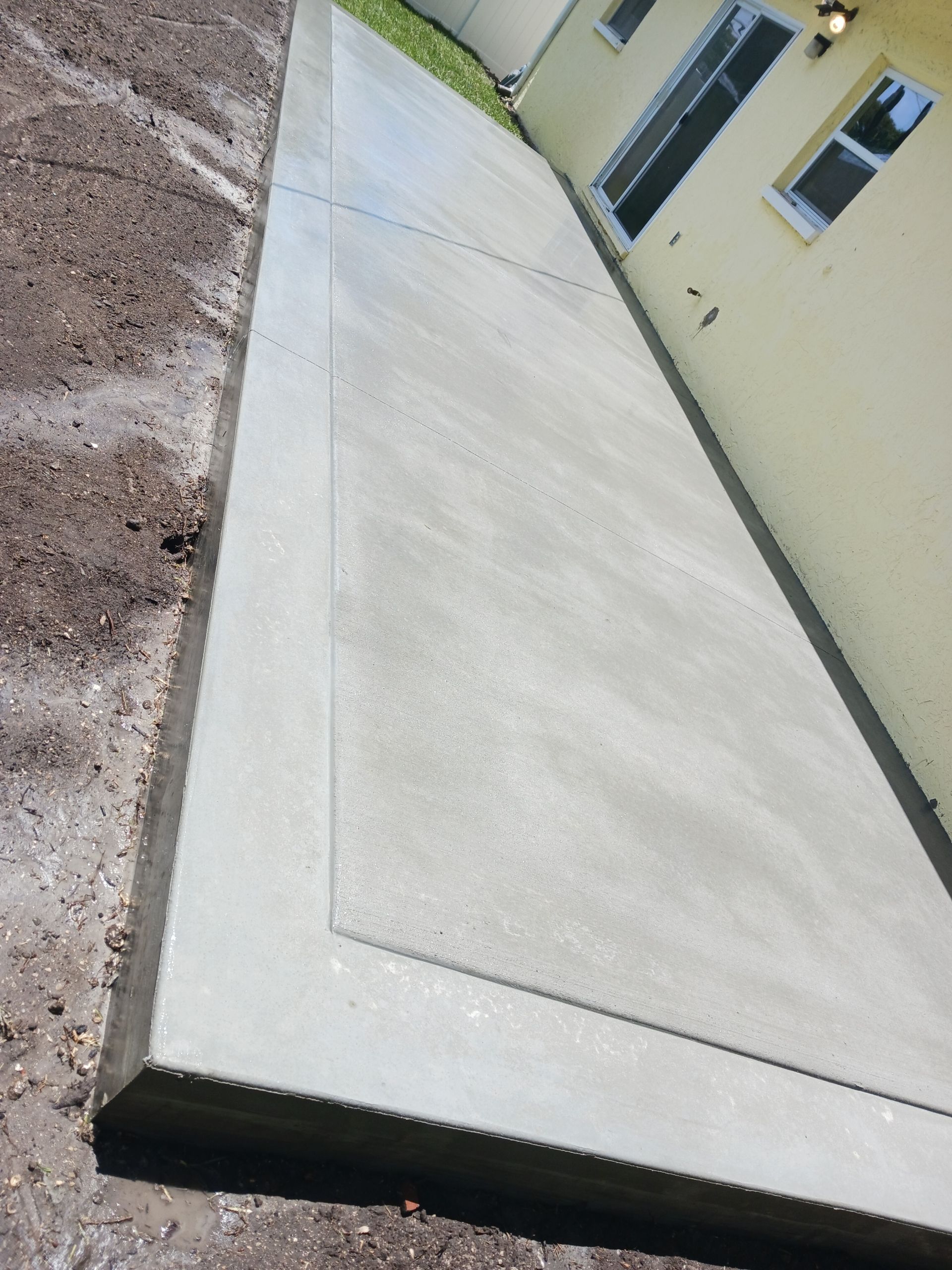 A concrete walkway is being built in front of a house