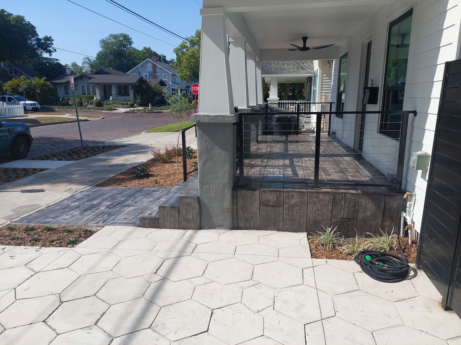 A white house with a porch and a fence in front of it.
