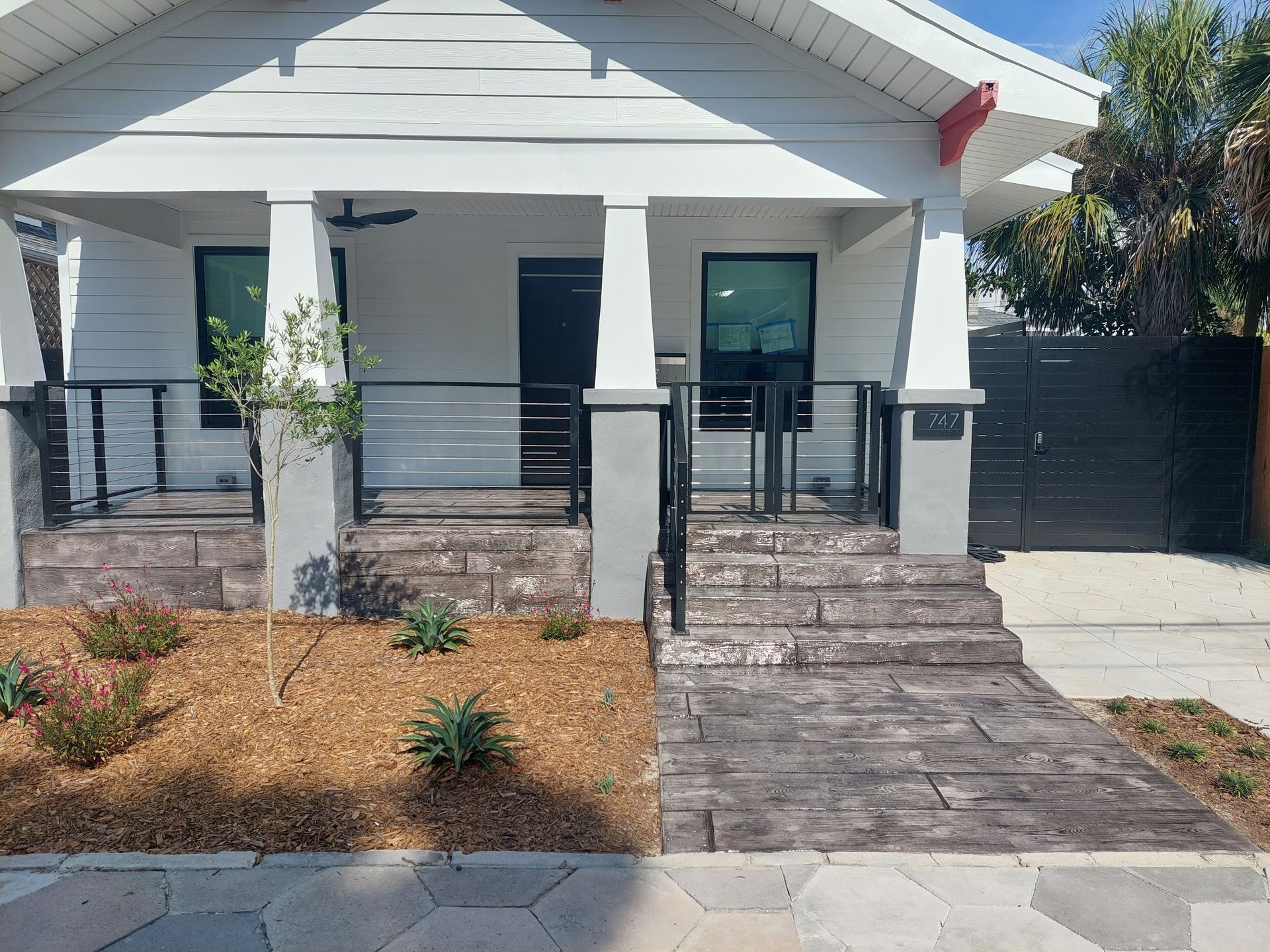 A white house with a black gate and stairs