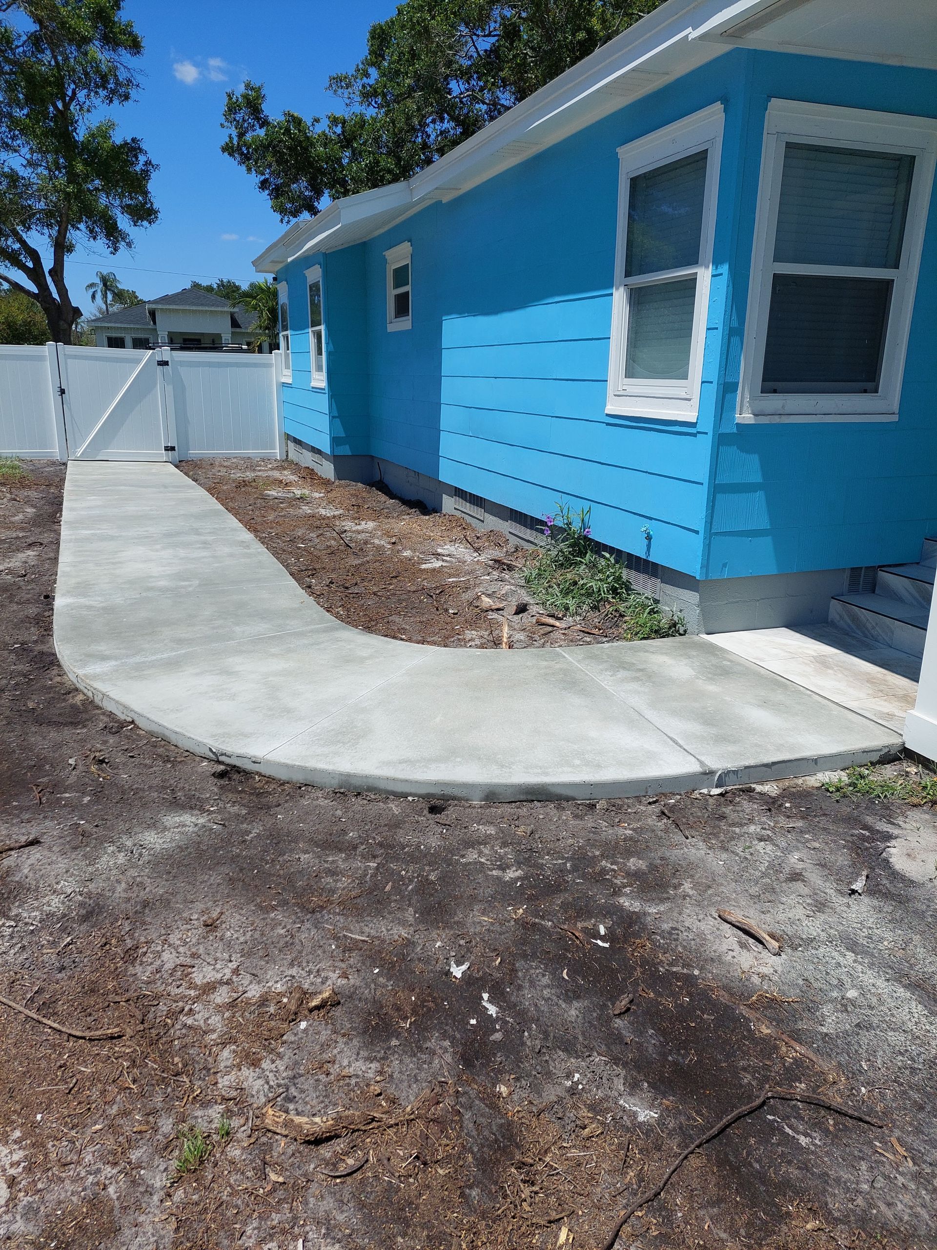 A blue house with a concrete walkway leading to it