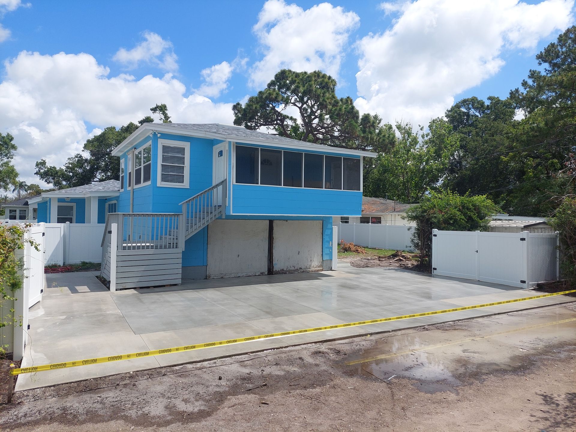 A blue house with a white fence and trees in the background