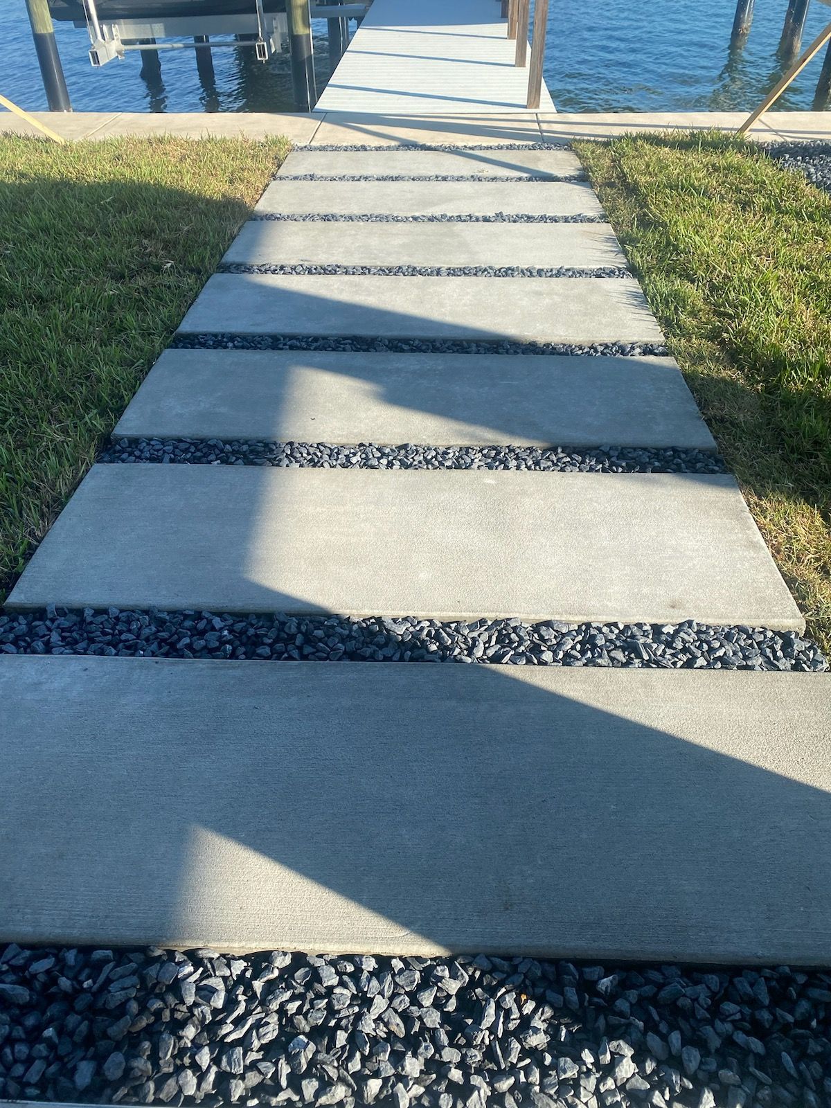 A concrete walkway leading to a dock next to a body of water.
