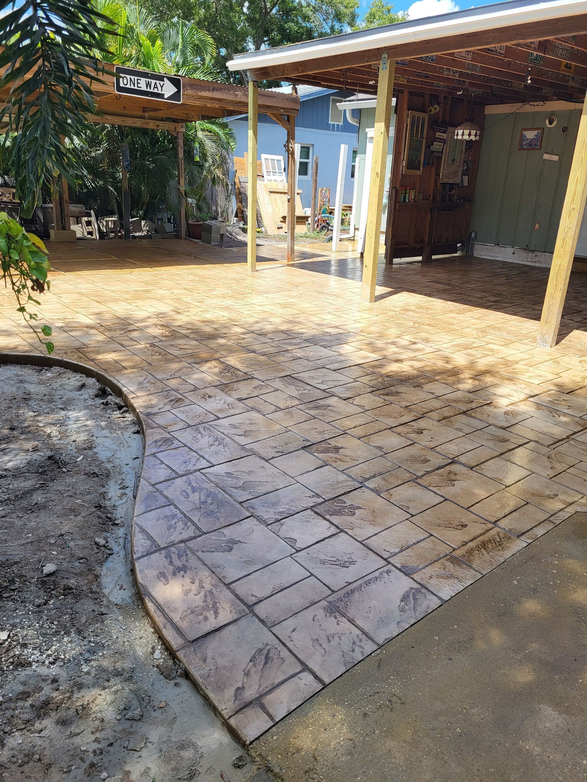 A patio with a carport and a walkway in front of a house.