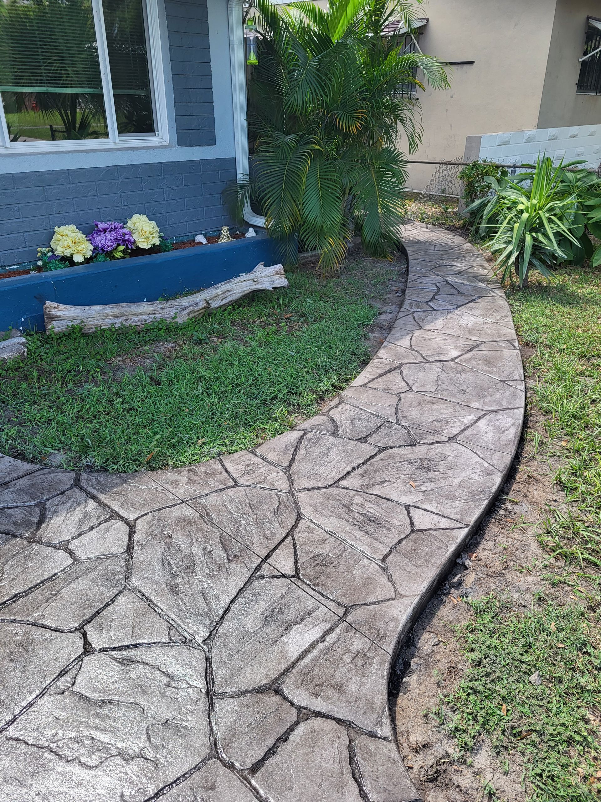 A stone walkway leading to a house in a yard.