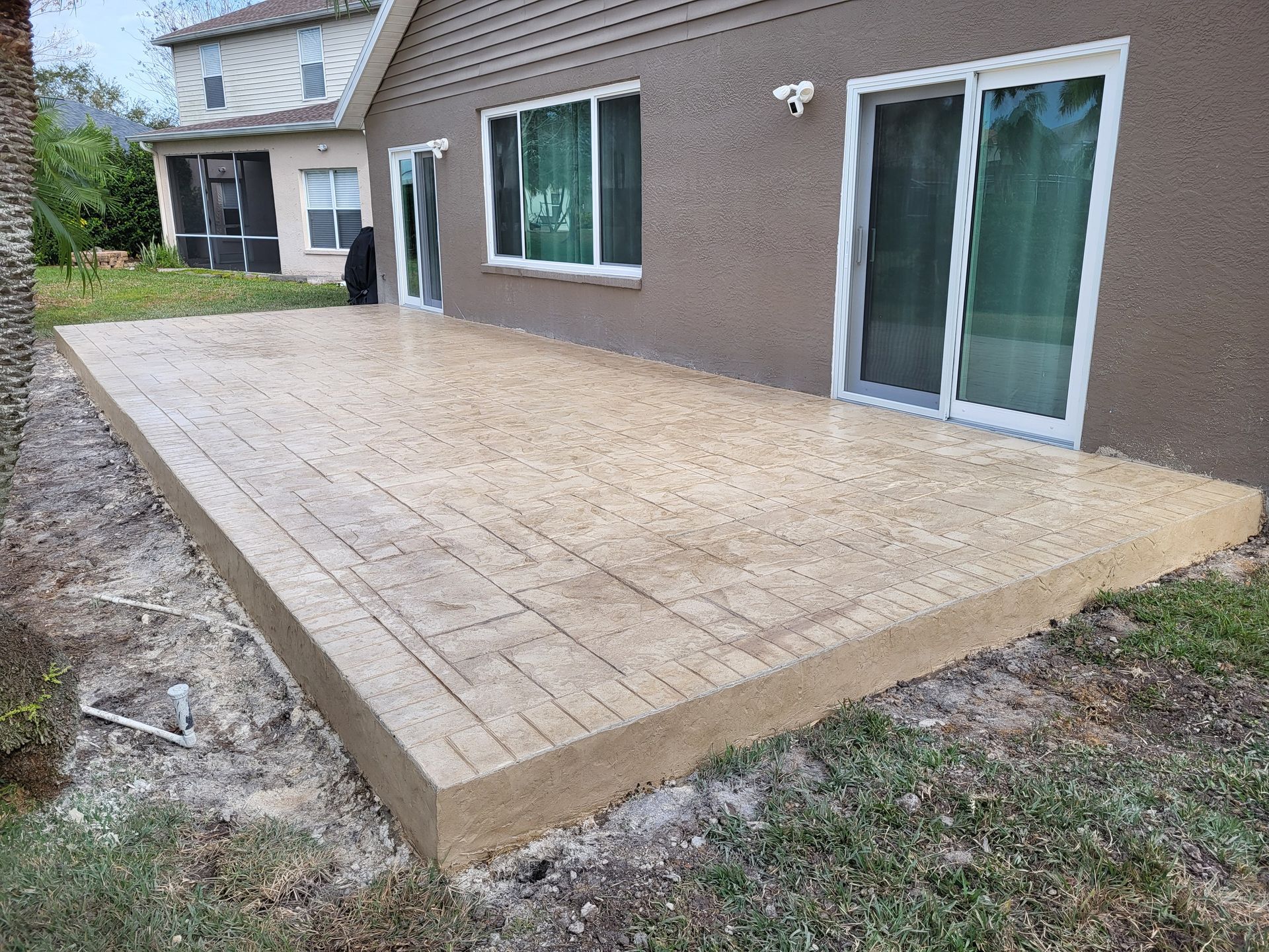 A concrete deck is sitting in front of a house with sliding glass doors.