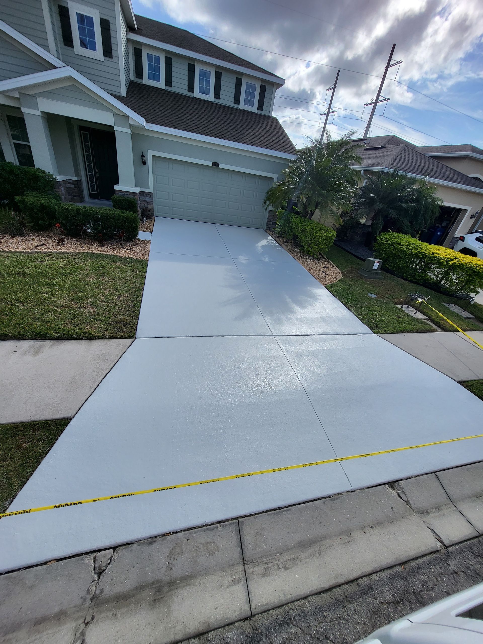 A driveway is being painted white in front of a house.