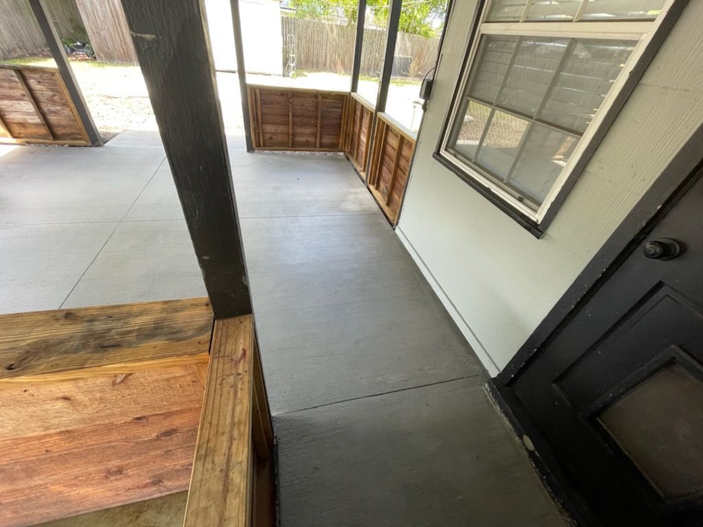 A concrete porch with a wooden railing and a black door.