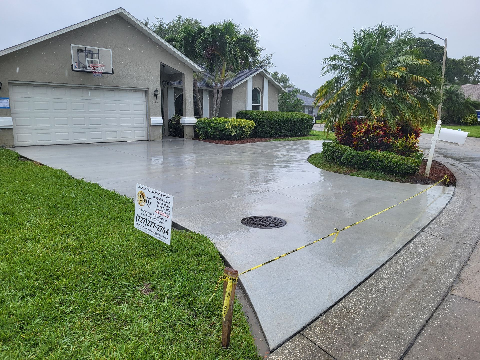 A concrete driveway in front of a house with a basketball hoop on it.