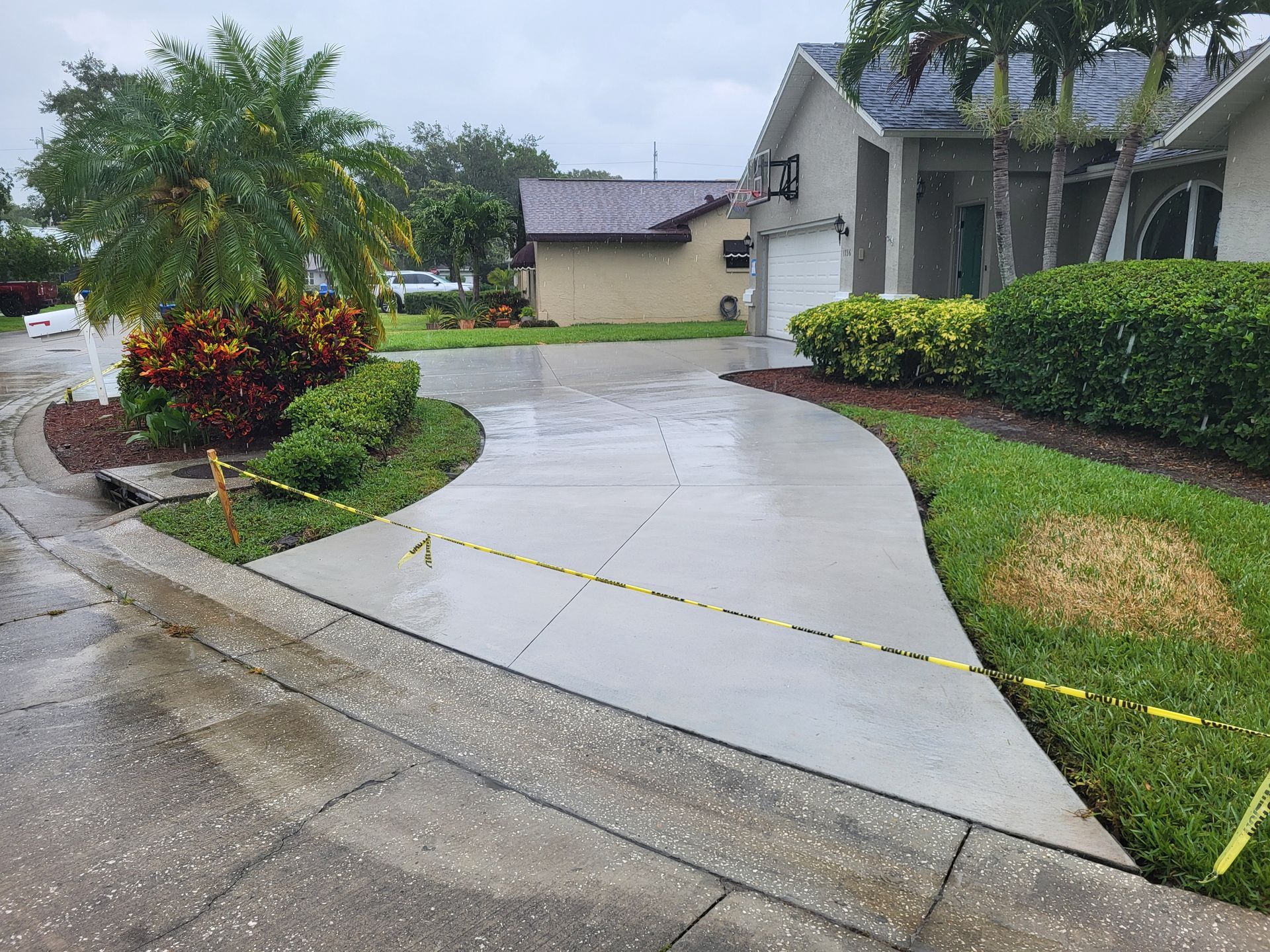 A concrete driveway is being cleaned in front of a house.