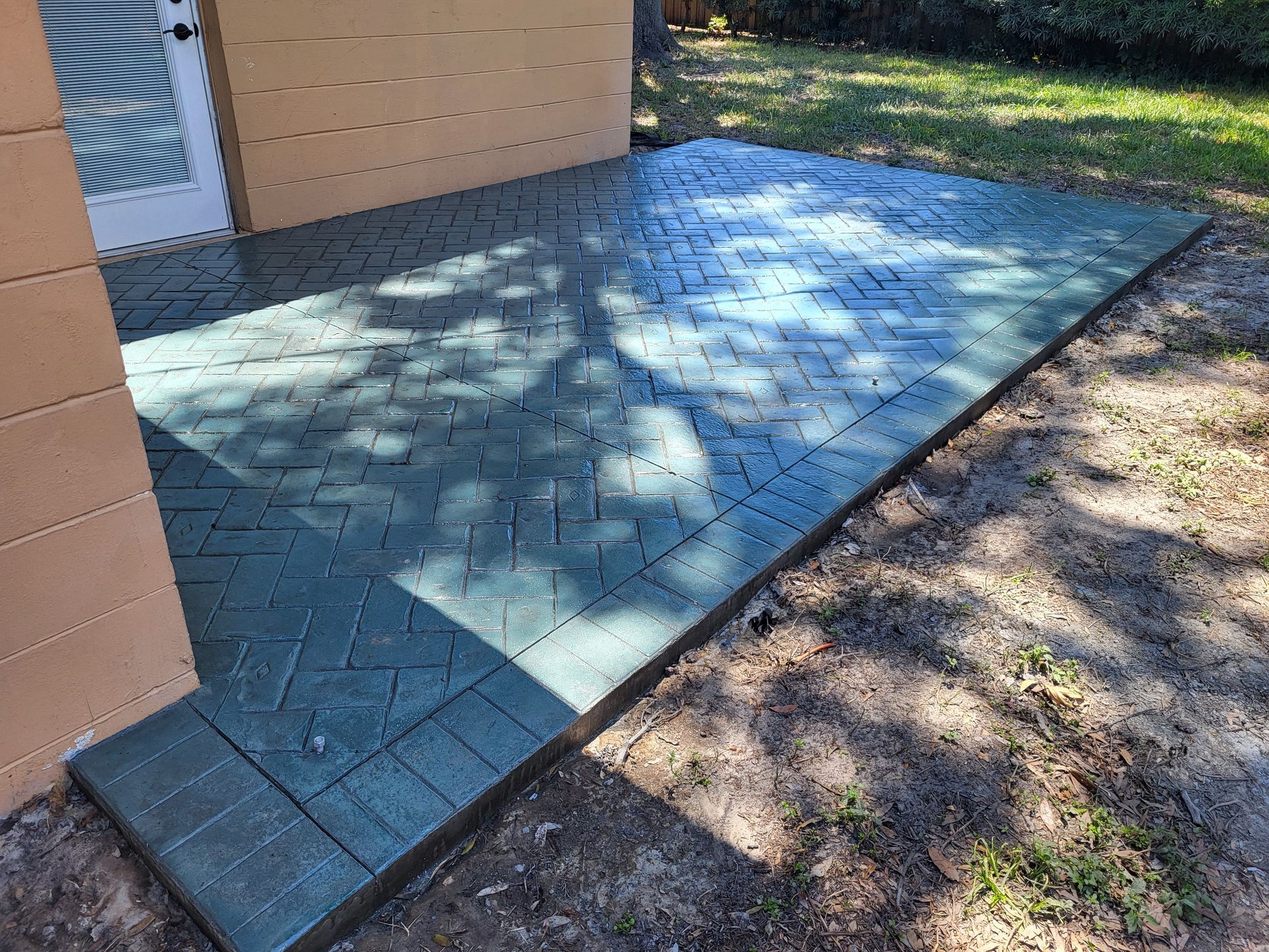 A green brick walkway is sitting in the dirt in front of a building.