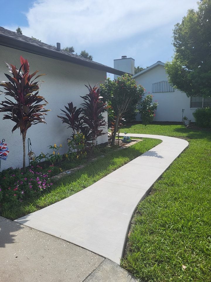 A white house with a concrete walkway leading to it.