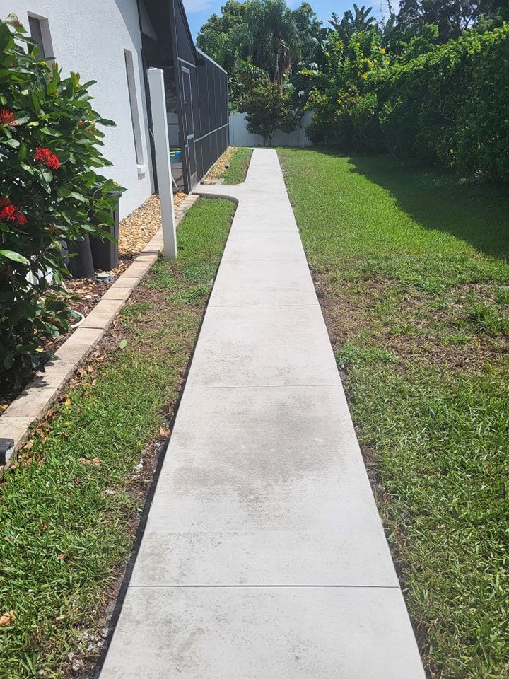 A concrete walkway leading to a house in a backyard