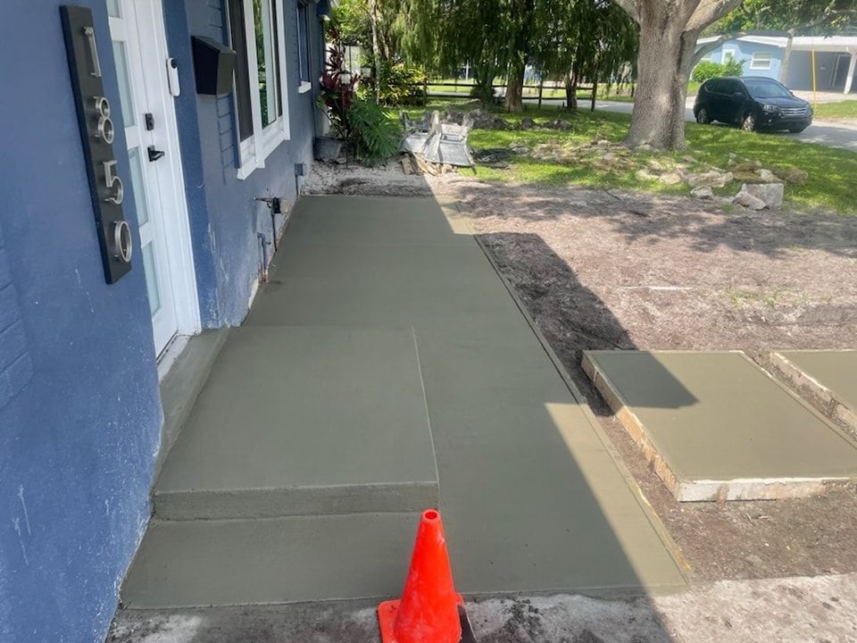 A concrete walkway is being built in front of a blue house.