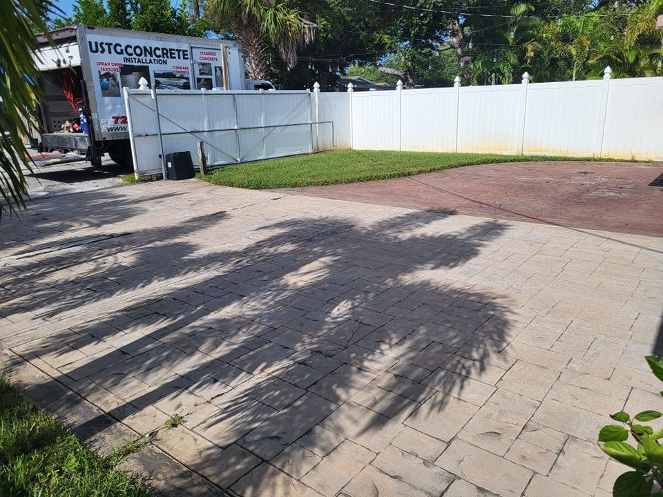 A white truck is parked in a driveway next to a white fence.