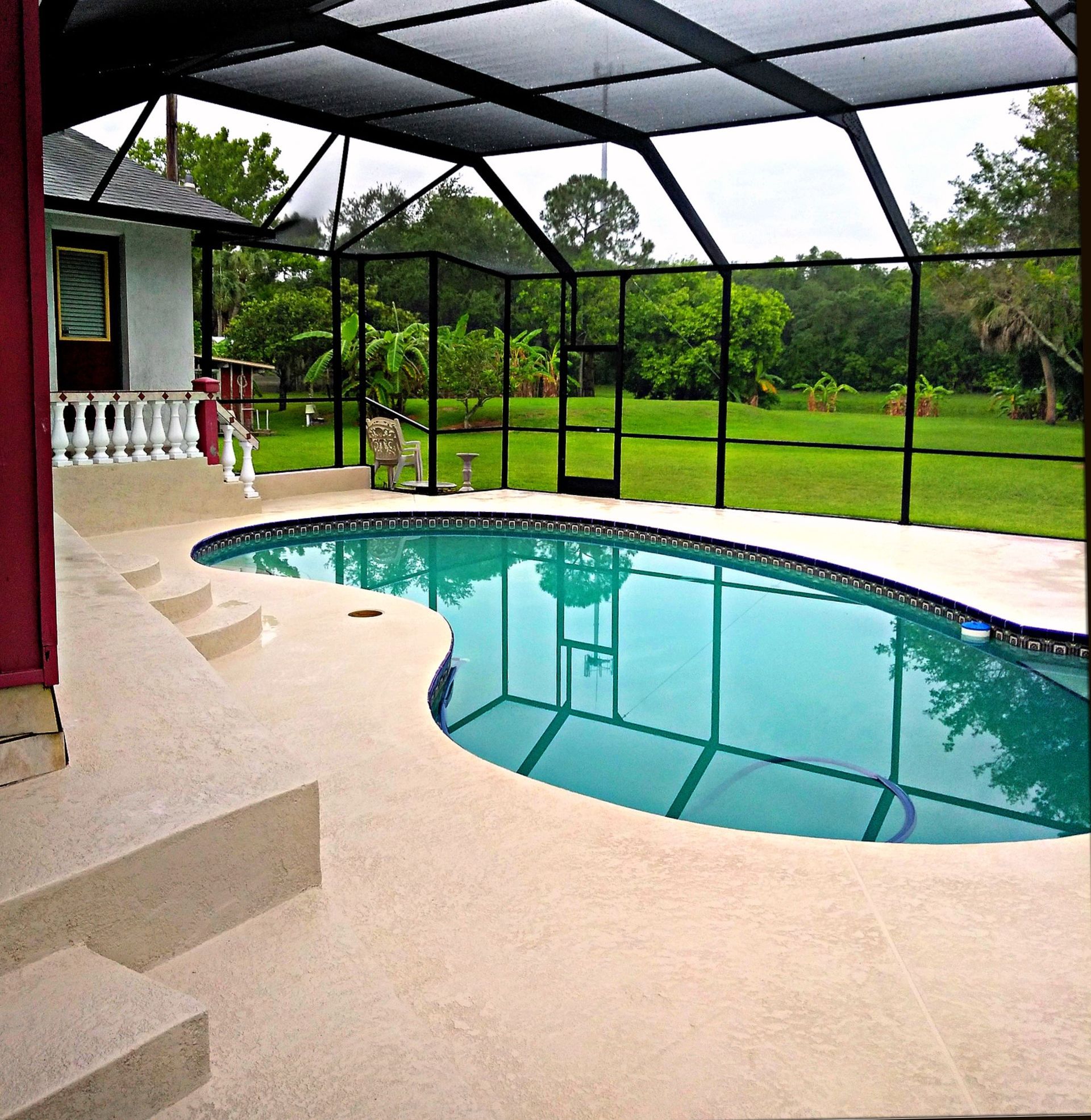A screened in area with a large swimming pool