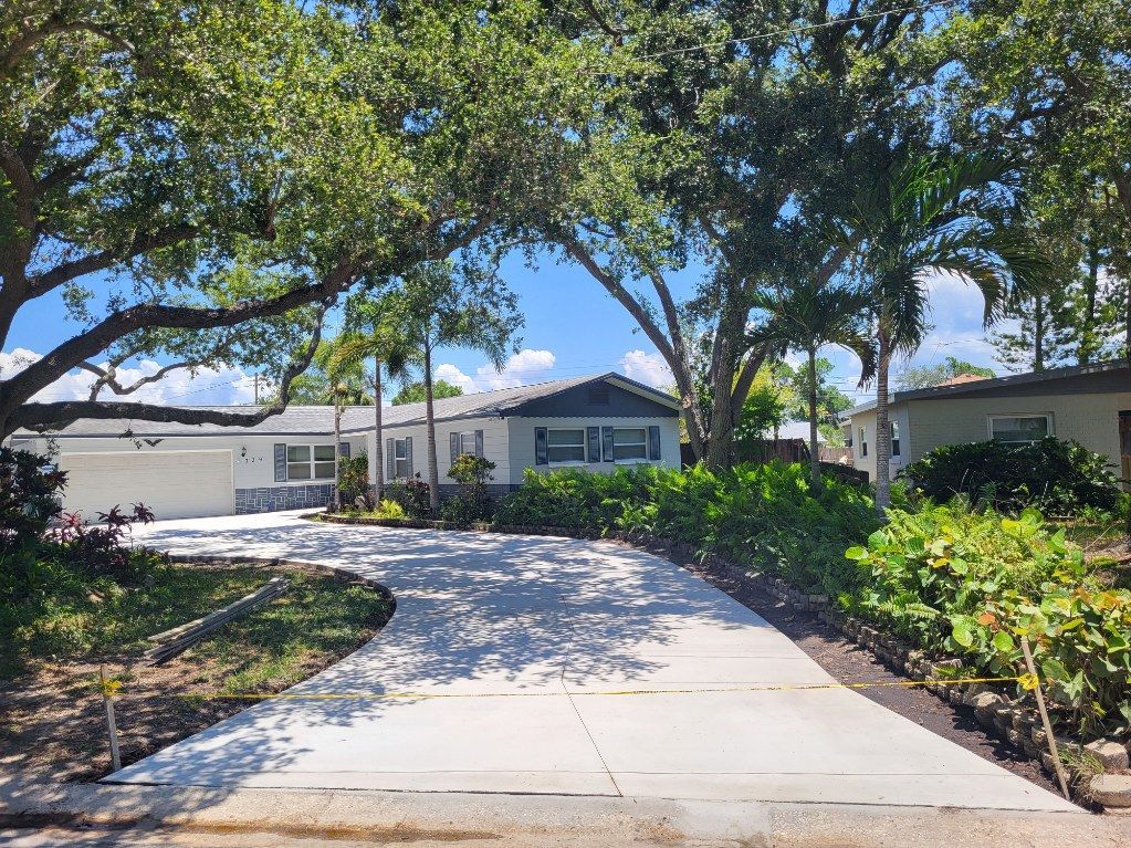 A concrete driveway leading to a mobile home surrounded by trees.