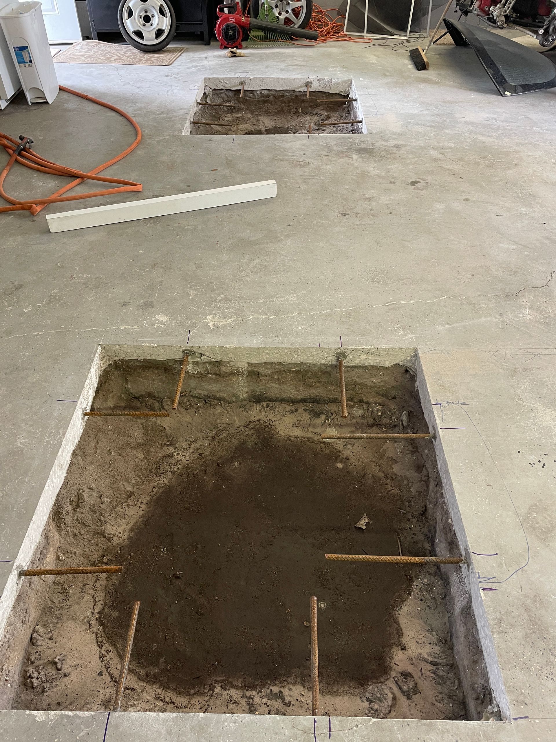 A hole in the floor of a garage is being filled with concrete.