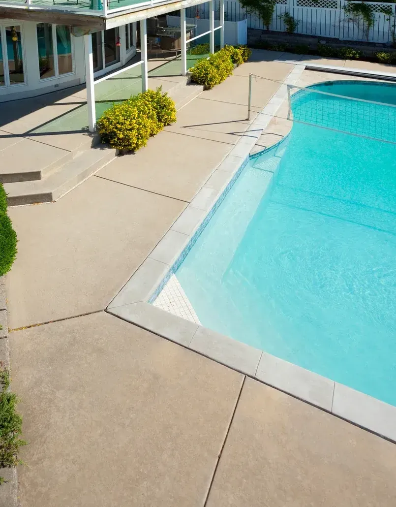 An aerial view of a large swimming pool in front of a house.