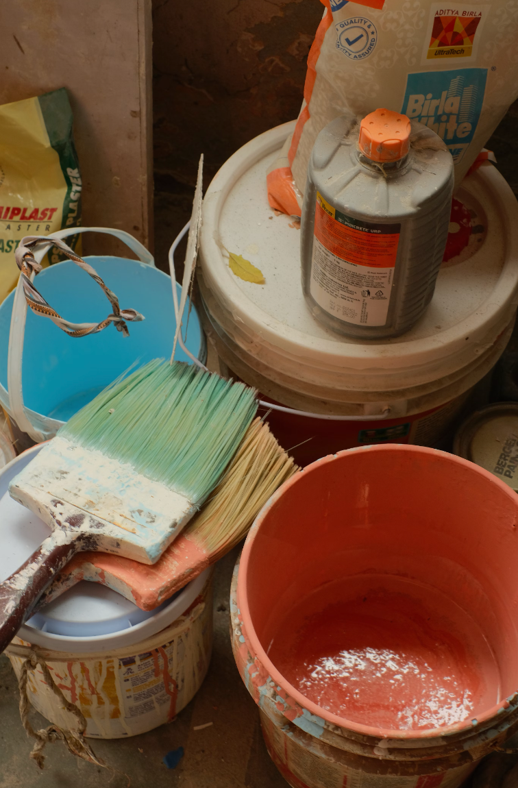 Buckets of paint and brushes are stacked on top of each other