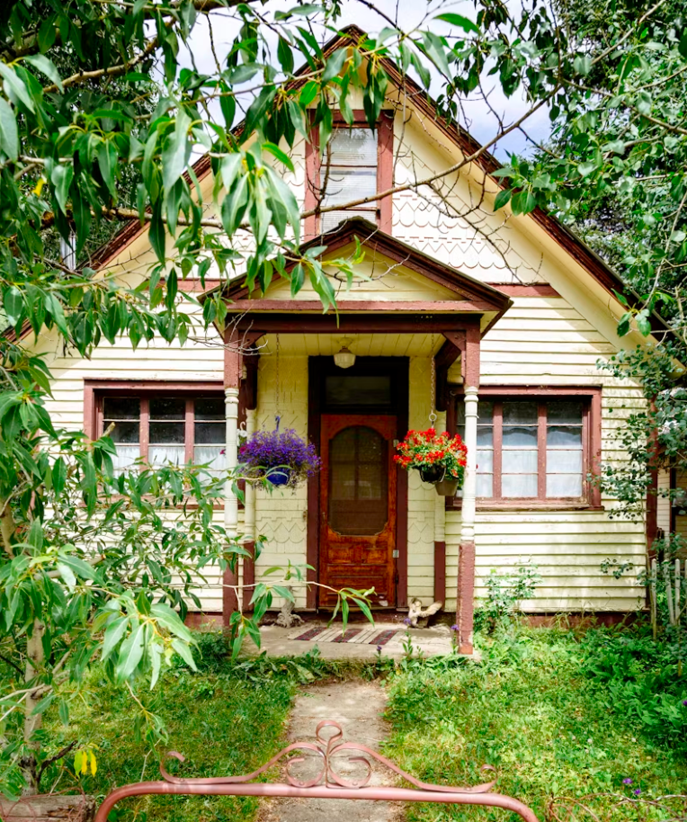 A small house with a porch and flowers on it