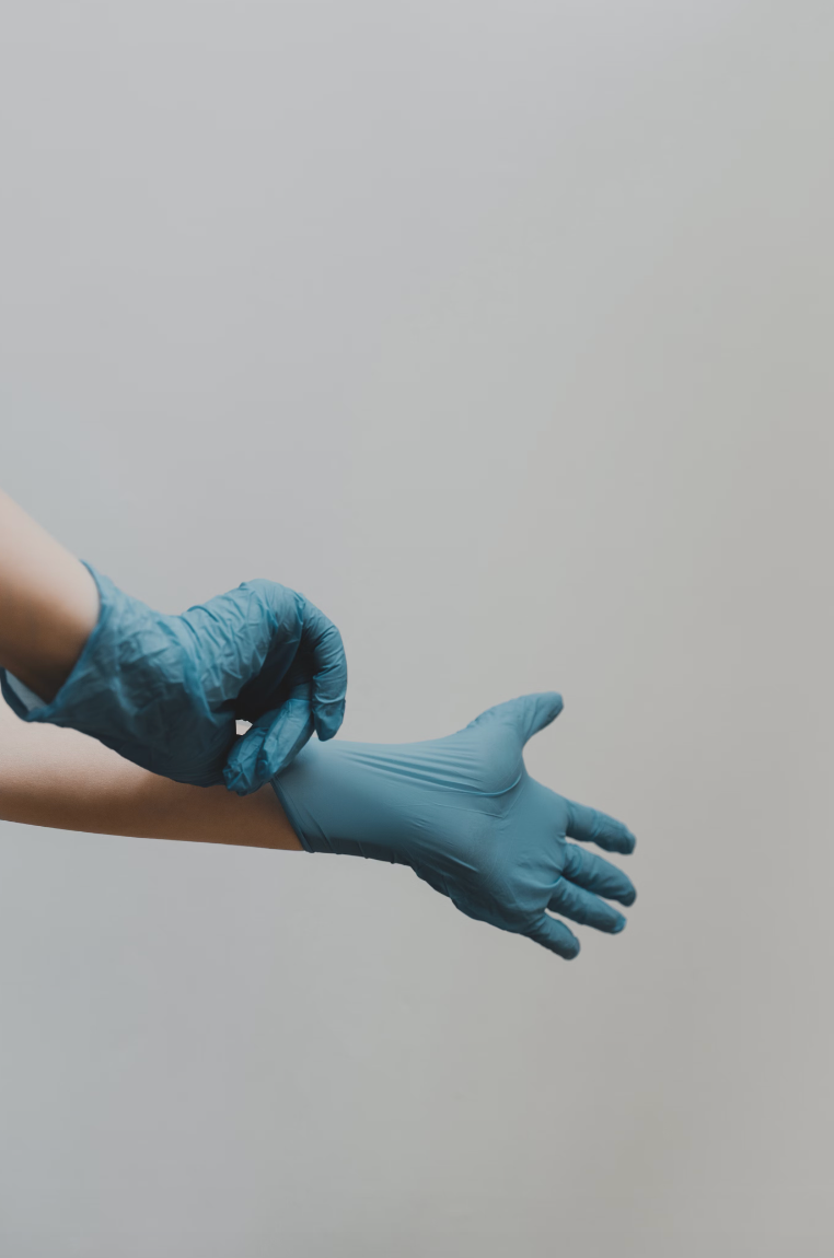 A person is putting on a pair of blue gloves.
