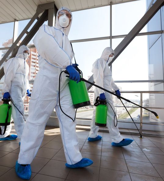 Protection of coronavirus biohazard. Men in respirators and protective suits cleaning public places