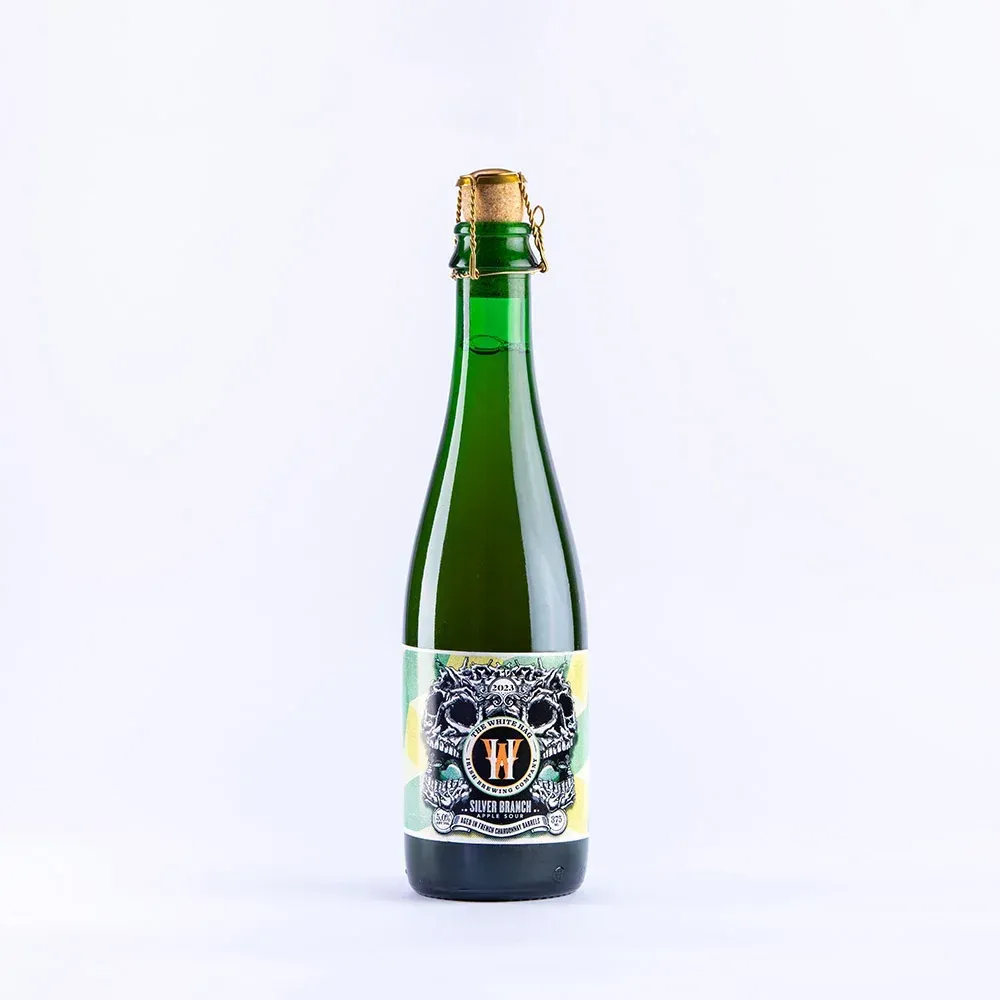 Groene bier fles met kurk en gouden beugel, label met schedels en hop – White Rooster Silver Branch 2023, bier.