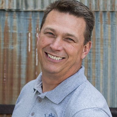 A man in a grey shirt is smiling for the camera.