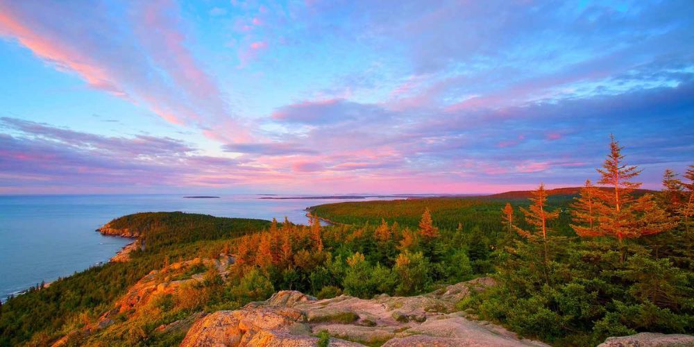 A view of a cliff overlooking the ocean at sunset.