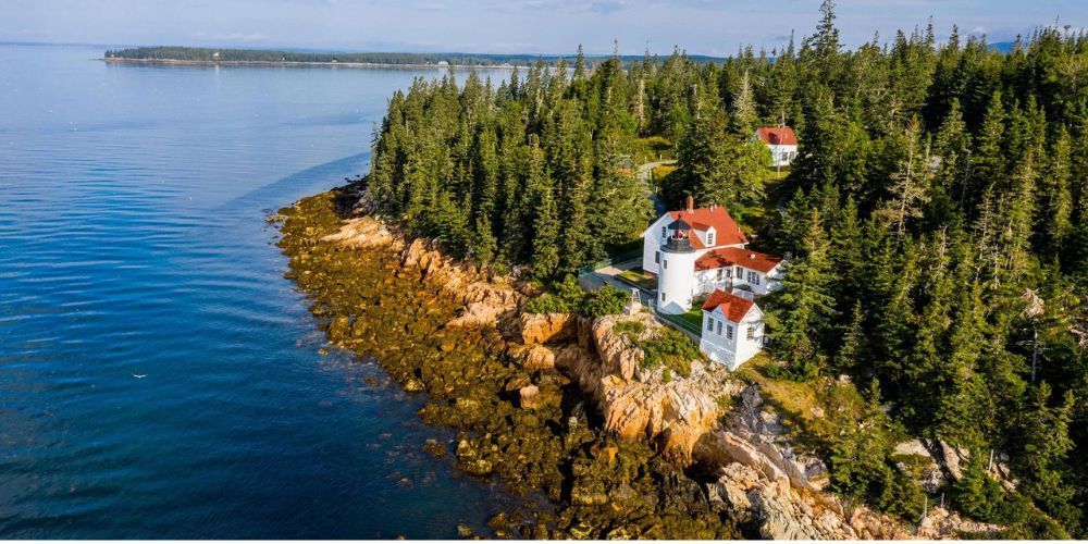 An aerial view of a lighthouse on a cliff overlooking the ocean.