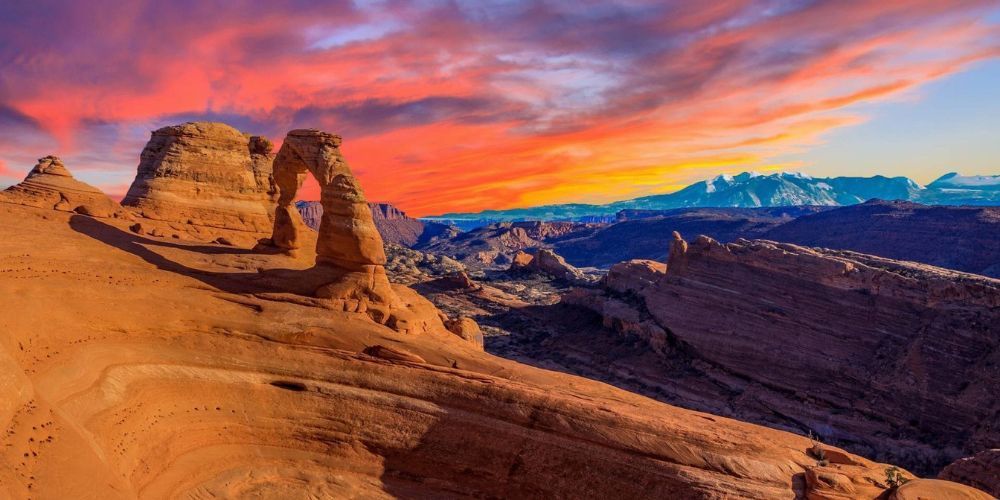 The delicate arch is a rock formation in the desert at sunset.