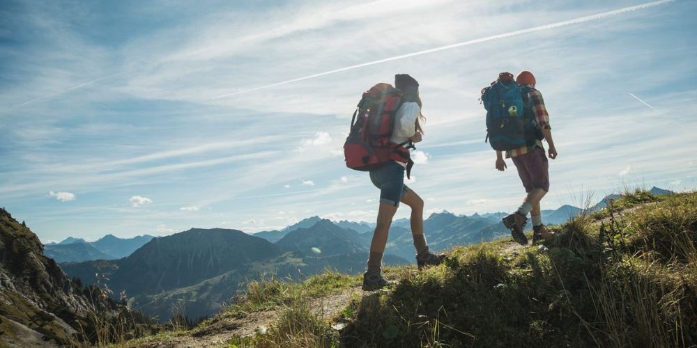 Two people with backpacks are hiking up a mountain.