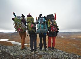 A group of people with backpacks standing on top of a mountain.