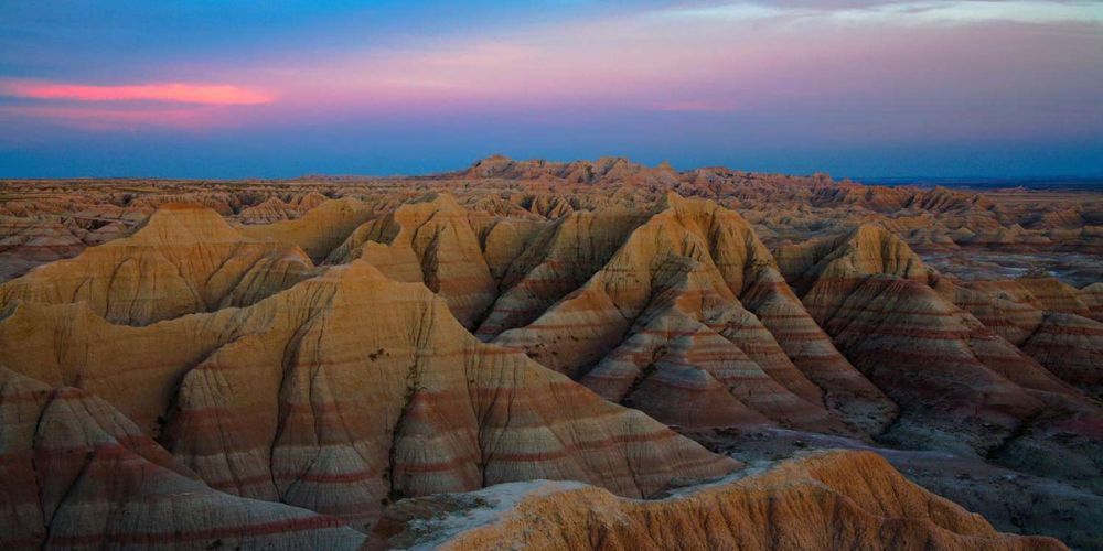 An aerial view of a desert landscape with a sunset in the background.