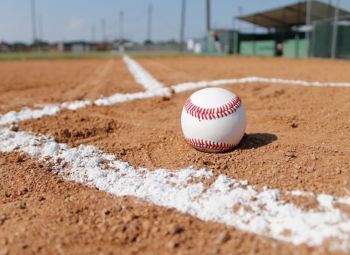 A baseball is sitting on the edge of a baseball field.