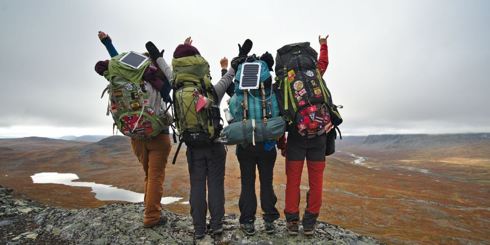 A group of people with backpacks are standing on top of a mountain.