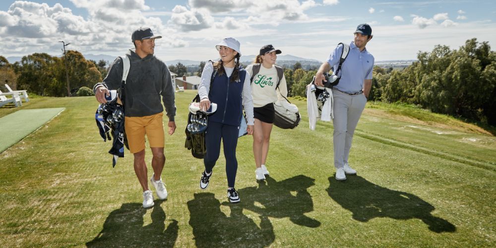 A group of people are walking down a golf course.