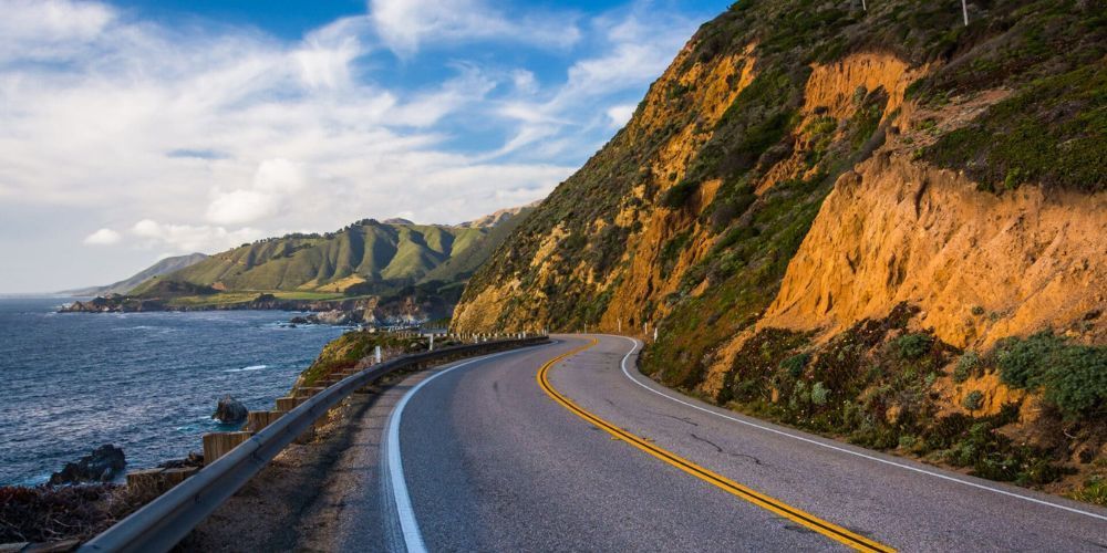 A road going down a cliff next to the ocean.