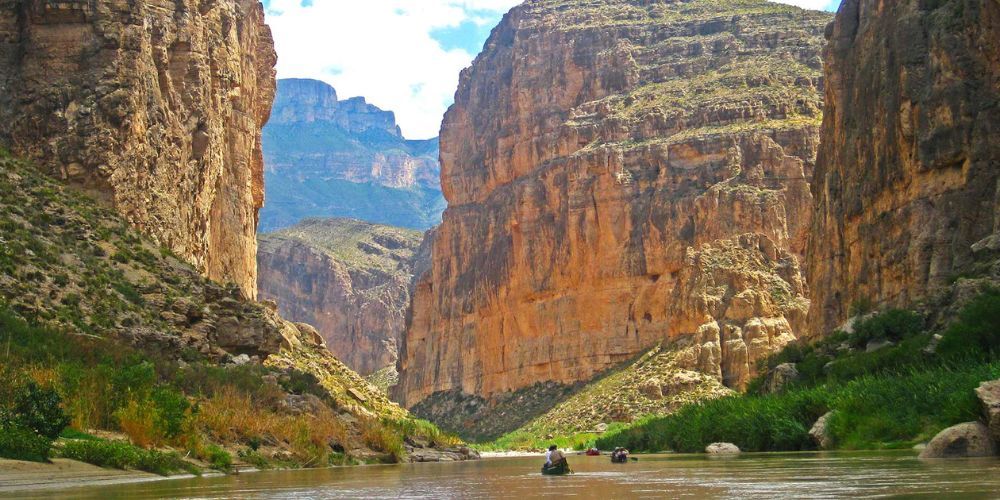 A river going through a canyon with mountains in the background.