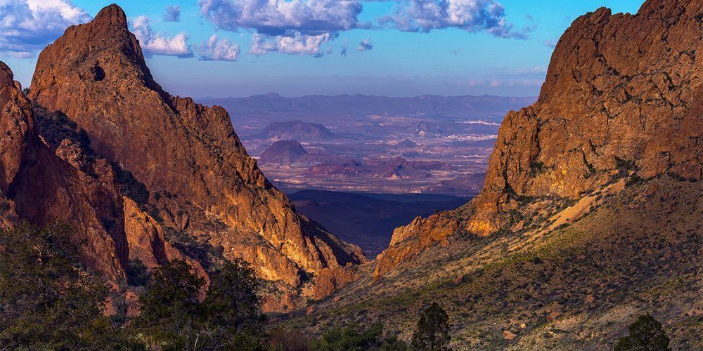 A view of a mountain range with a city in the distance.