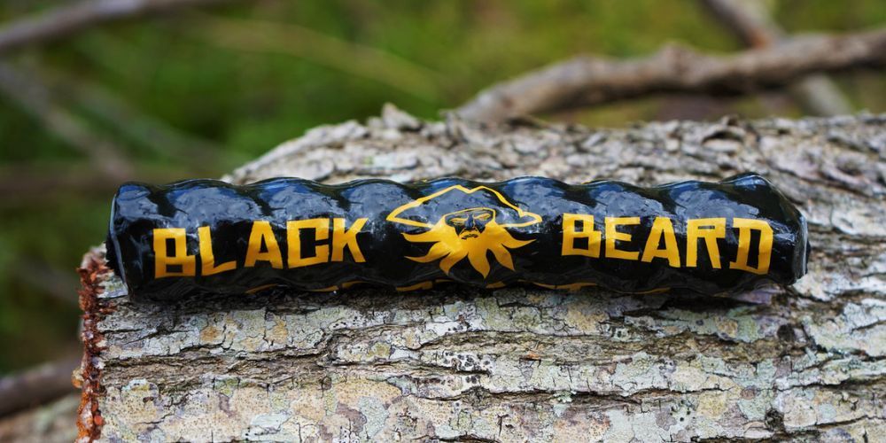 A black beard bracelet is sitting on top of a piece of wood.