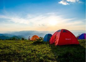 A group of tents are sitting on top of a grassy hill.