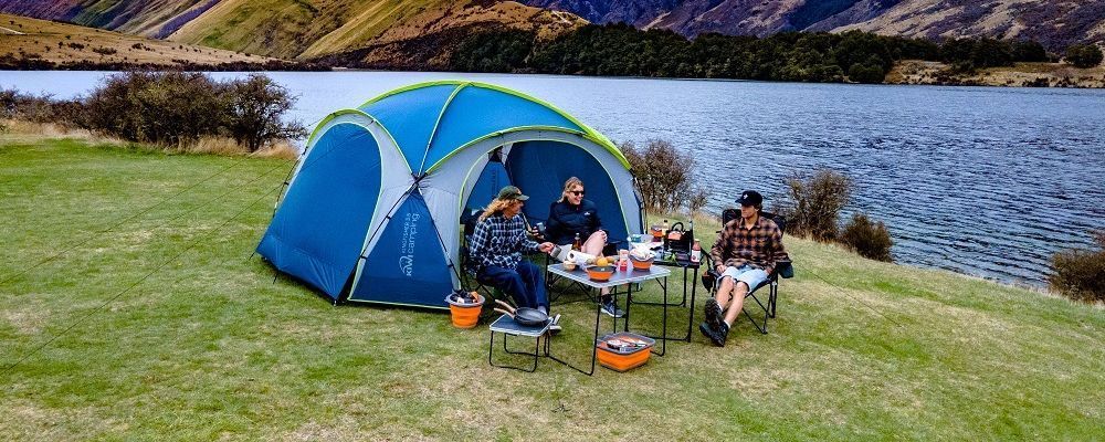 A group of people are sitting at a table in front of a tent.