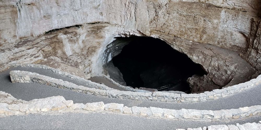 A cave with stairs leading up to it and a road going through it.