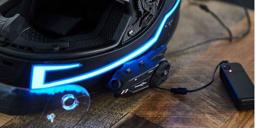 A motorcycle helmet with a blue light on it is sitting on a wooden table.